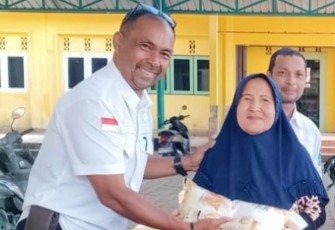 Camat Tambelan Asmawi saat menyerahkan beras pada ibu Lansia