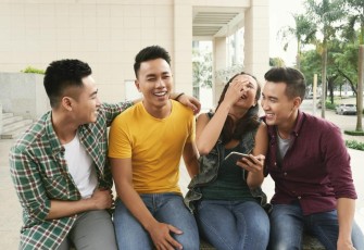 Foto Group of young Asian men and girl sitting together in urban street and laughing (Freepik.com)