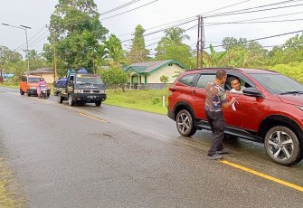 Babinsa Koramil 1710-07/Mapurujaya saat Bagikan Bendera Merah Putih Kepada Pengguna Jalan