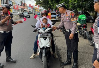 Personil Polres Bitung saat membagikan bendera merah putih kepada pengguna jalan