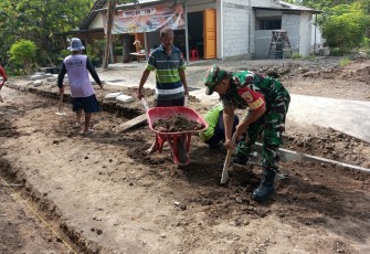 Babinsa Desa Pulerejo Bersama Warga Sukseskan Kerja Bakti Pemasangan Paving