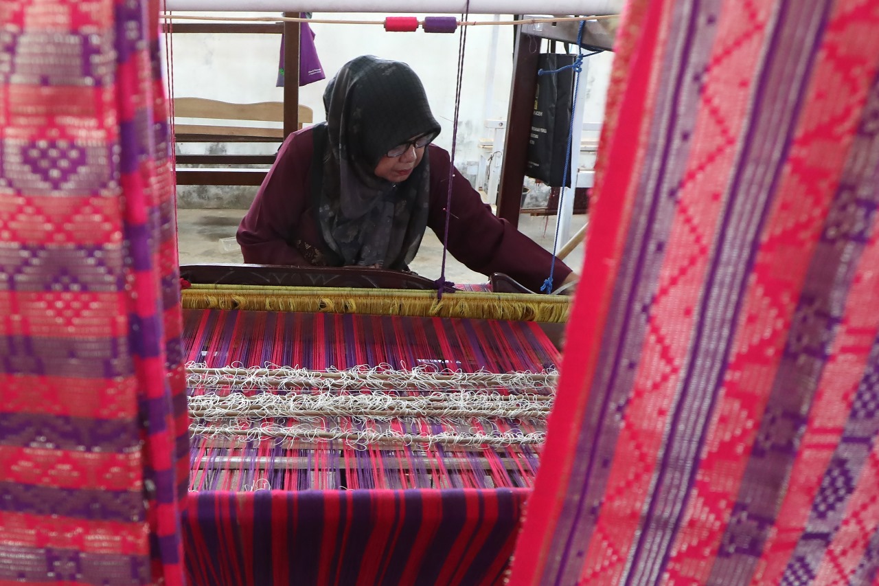Perajin Usaha Mikro, Kecil dan Menengah (UMKM) menyelesaikan tenun tradisional motif khas Aceh di tempat produksi Desa Lamgugob, Banda Aceh, Aceh, Senin (22/7/2024). Pelaku usaha rumahan dan UMKM mulai meningkatkan produksi kerajinan hingga 80 persen untuk dijajakan saat berlangsungnya PON XXI Aceh-Sumut awal September mendatang. ANTARA FOTO/Irwansyah Putra/Spt.