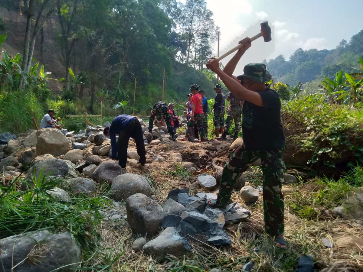 Personel Satgas TMMD Ke 117 Kodim 0803/Madiun bersama warga bergotong royong membelah baru kali untuk pembangunan jembatan yang akan menghubungkan dua desa yakni desa Kare dan desa Kepel 