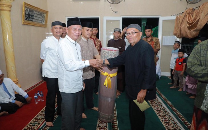 Plt. Bupati Asahan, Surya saat menyerahkan bantuan kepada Ketua BKM Musholla Ikhwanul Munir.