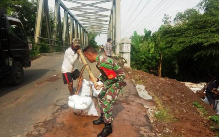 Warga dibantu personel TNI pertebal Tanggul Babakan