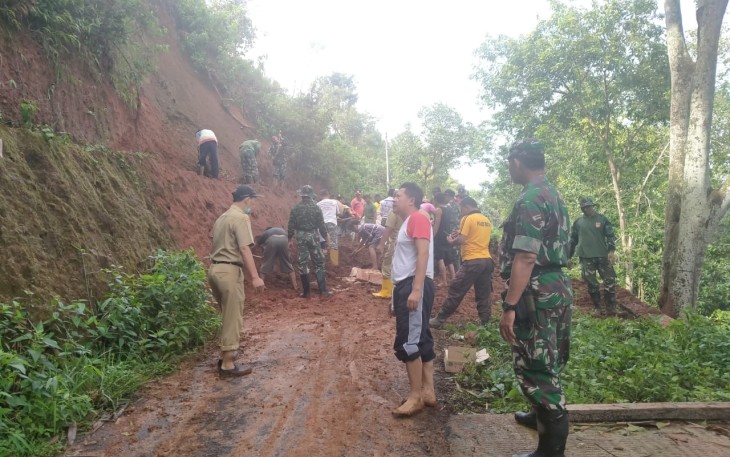 Anggota TNI bersama warga saat bersihkan material longsor