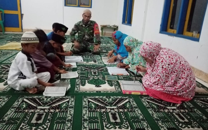 Babinsa Koramil 1905/Jatiluhur Kodim 0619/Purwakarta Serka Maman Suparman Saat Sedang Mengajari Anak-anak Desa Cibinong Membaca dan Menghafal Al-Quran (Foto/Aik NH)