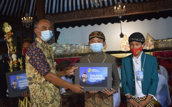 Kepala Dinas Kebudayaan Kota Surakarta, Agus Santoso saat menyerahkan piala Dalang Mumpuni dalam Festival Dalang Cilik Kota Surakarta 2021 Kategori A untuk siswa SD