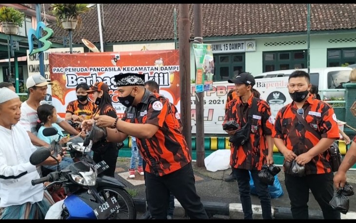 Ketua PAC PP Dampit, H. Nanang Qosim, saat membagikan takjil kepada pengguna jalan, Sabtu (30/4/2022)