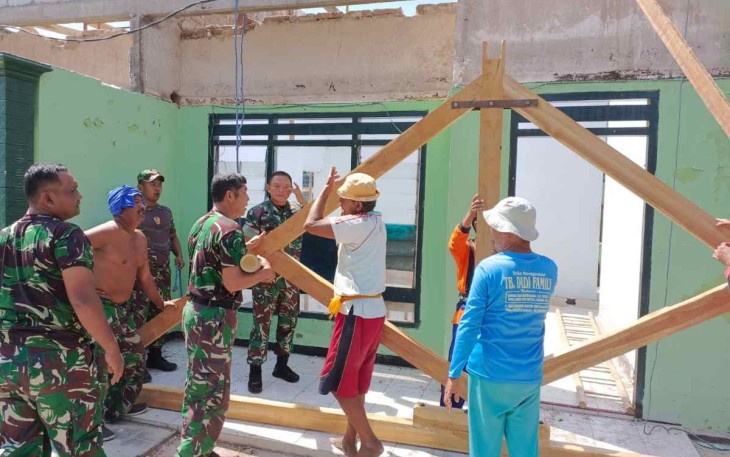 Dandim saat membantu angkat palang kuda atap bersama anggota