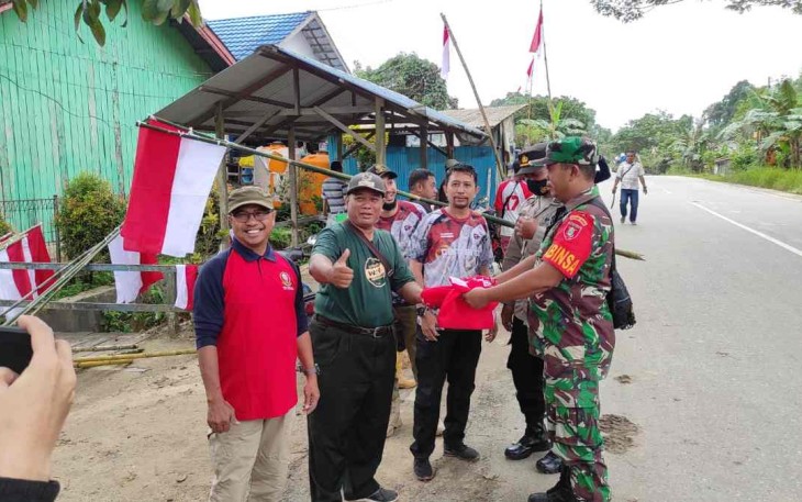 Danramil 04/Sangasanga Kapten Inf Priyanto saat bagikan bendera merah putih kepada warga 