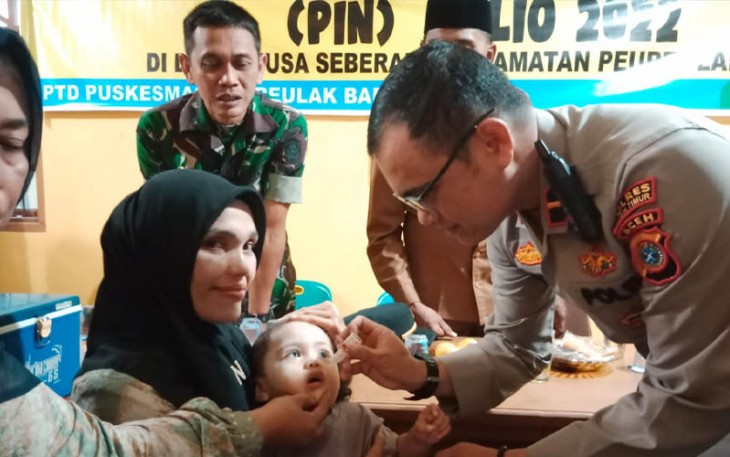 Polisi saat berikan vaksin polio kepada balita.