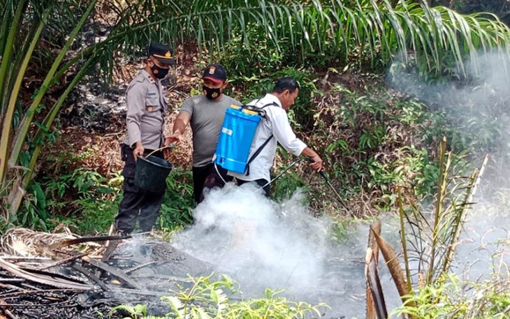 Polisi dan warga saat padamkan api kebakaran lahan