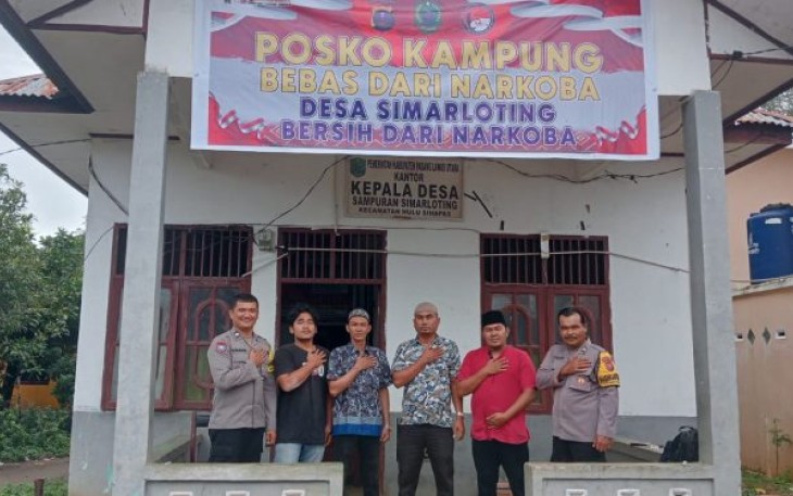 Bhabinkamtibmas Polsek Padang Bolak, Aipda Nyamano Manik, memasang spanduk Posko Kampung Bebas dari Narkoba, Selasa (24/10/2023) siang.