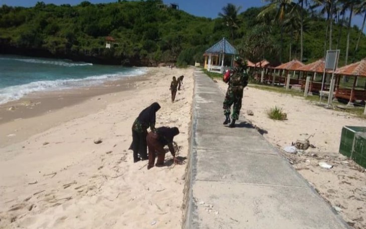 Babinsa Koramil 0801/12 Pringkuku saat Gelar Aksi Sosial Bersihkan Pantai.