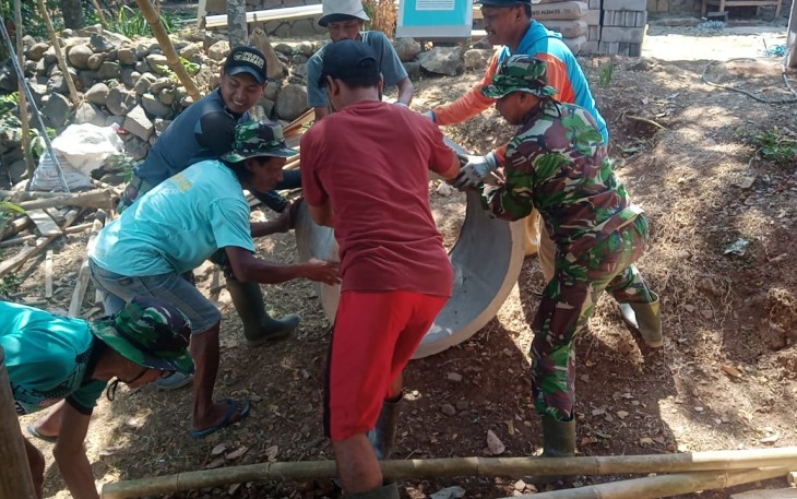 "Satgas TMMD bersama warga sedang menurunkan Bis"