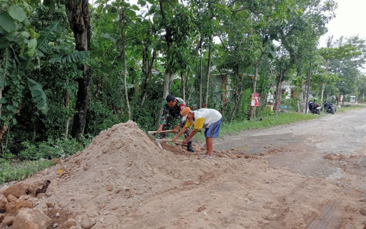 Babinsa Koramil Balerejo Bantu Warga Perbaiki Jalan Berlubang