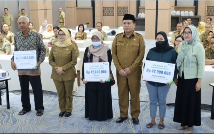 Bupati Blitar Rini Syarifah Didampingi Sekda Kabupaten Blitar Izul Marom Bersama Kepala BPJS Ketenagakerjaan Cabang Blitar Venina Sesuai Menyerahkan Santunan JKM dan Beasiswa kepada Peserta BPJS Ketenagakerjaan 