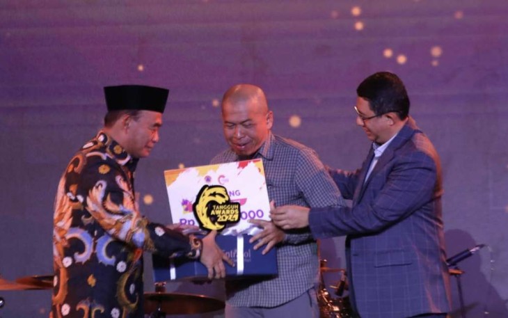 Menko PMK Muhadjir Effendy (kiri) bersama Kepala BNPB Letjen TNI Suharyanto (kanan) menyerahkan trofi Penganugerahan Tokoh Inspiratif Tangguh Awards 2024 BNPB kepada Boy Tri Harjanto di Jakarta, Sabtu (21/9).