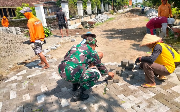 Babinsa Koramil Geneng Bantu Warga Pasang Paving Jalan Desa