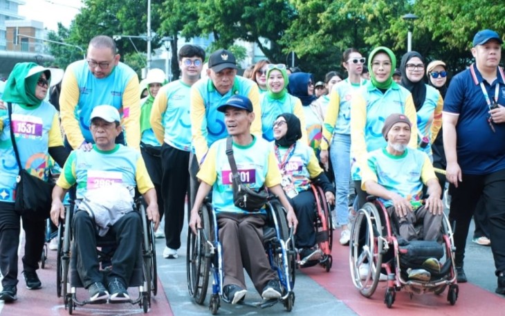 Wamensos Agus Jabo Priyono (tengah) saat mendorong kursi roda penyandang disabilitas dalam ajang Fun Walk HDI 2025 di bundaran HI Jakarta, Minggu (7/12)
