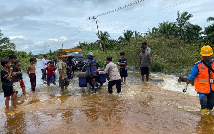 Polsek Singkil saat melakukan pengaturan lalu lintas di ruas jalan Singkil – Sebatang tepatnya Desa Pea Bumbung, Kecamatan Singkil, Kabupaten Aceh Singkil, yang putus akibat tergerus derasnya aliran air pascahujan lebat yang melanda wilayah tersebut, Minggu (23/11/2025)