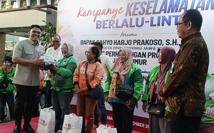 Anggota DPRD Jatim Cahyo Harjo Prakoso saat membagikan helm gratis ke perwakilan Ojol