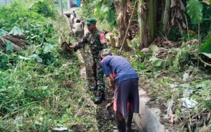 Babinsa Kelurahan Sogaten, Koramil 0803-02/Madiun, Serka Rofik Sutrisno, bersama warga RT 02 RW 01 saat melaksanakan kerja bakti pembersihan saluran air.