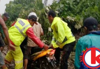 Warga saat membantu pengendara motor melintas di lokasi longsor
