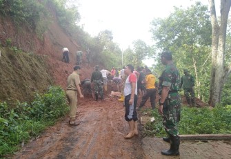 Anggota TNI bersama warga saat bersihkan material longsor