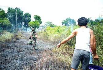 Babinsa Padamkan Kebakaran Hutan Ilalang di Kelurahan Manembo-Nembo