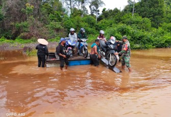 Babinsa Bantu Seberangkan Motor dan Warga yang Melintas