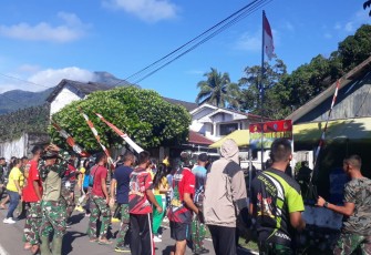 Personil satgas TMMD bersama warga sekitar saat berjemur di pagi hari