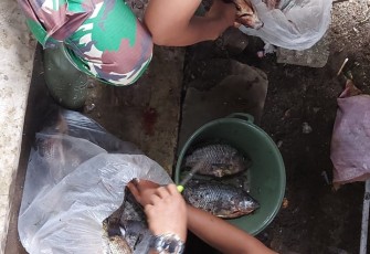 Personil satgas TMMD ke 111 kodim 1310/Bitung saat bantu warga bersihkan ikan
