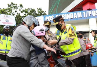 Kapolda Riau Irjen Pol Mohammad Iqbal saat berikan helm dan memakaikannya ke anak pengendara motor. Selasa (4/10)