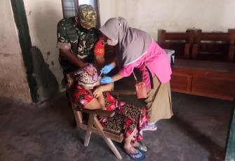 Serda Slamet Anggota Koramil 0803-16/Wonoasri bersama Perangkat Desa dan Tenaga Kesehatan, saat melaksanakan serbuan vaksinasi dosis ketiga bagi ODGJ di Desa Wonoasri,Kec. Wonosari, Kab. Madiun, Selasa (30/8/2022).