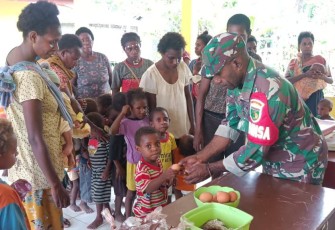 Babinsa Koramil 1710-03/Kuala Kencana saat Bagikan Makanan Tambahan Kepada Anak di Wilayah Binaan