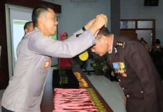 Kapolres Tuban AKBP Rahman Wijaya saat mengalungkan medali wisuda purna bhakti personelnya, Selasa (3/1)
