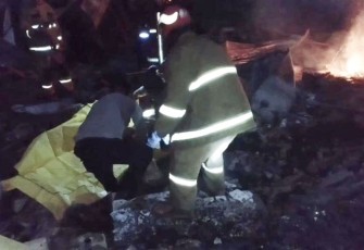 Petugas kepolisian evakuasi korban terbakar di TKP lapak barang bekas terbakar di kampung Tapos desa Cibinong, Minggu (8/1)