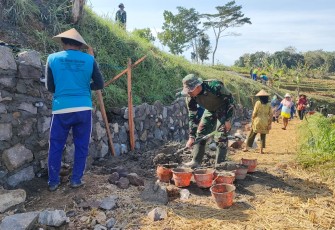 "Salah seorang anggota satgas TMMD sedang mengisi adukan cor ke ember"
