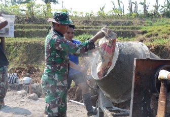 "Anggota Satgas TMMD sedang menyiapkan adukan semen"