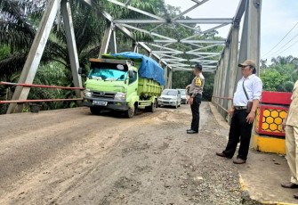 Bhabinkamtibmas Polsek Batik Nau Saat Mengatur Lalin  di Jembatan Desa Batik Nau