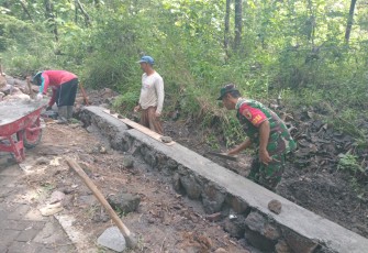 Babinsa Koramil Widodaren  Kodim 0805/Ngawi Serru Joko Priyanto tampak sedang membantu membenahi pembangunan talut dan irigasi bersama masyarakat di Desa Widodaren, Kecamatan Widodaren, Minggu (12/01/2025)