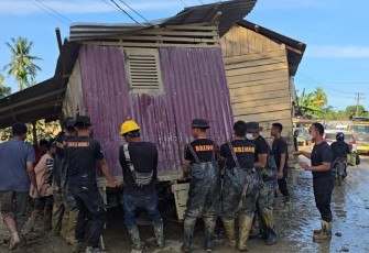 Brimob saat Pindahkan Rumah Terseret Banjir yang Melintang di Jalan Nasional Tamiang–Langsa