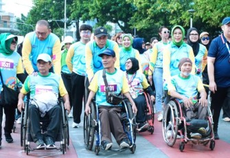 Wamensos Agus Jabo Priyono (tengah) saat mendorong kursi roda penyandang disabilitas dalam ajang Fun Walk HDI 2025 di bundaran HI Jakarta, Minggu (7/12)