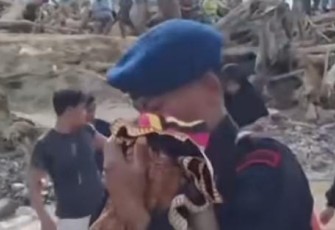 Seorang anggota Brimob terlihat menggendong seorang bayi menyeberangi jembatan darurat yang hampir roboh diterpa derasnya arus sungai pascabanjir.